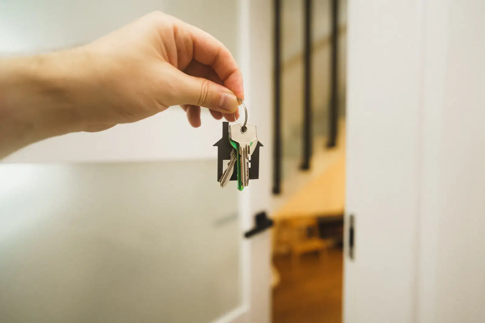A hand holding a set of house keys at a door