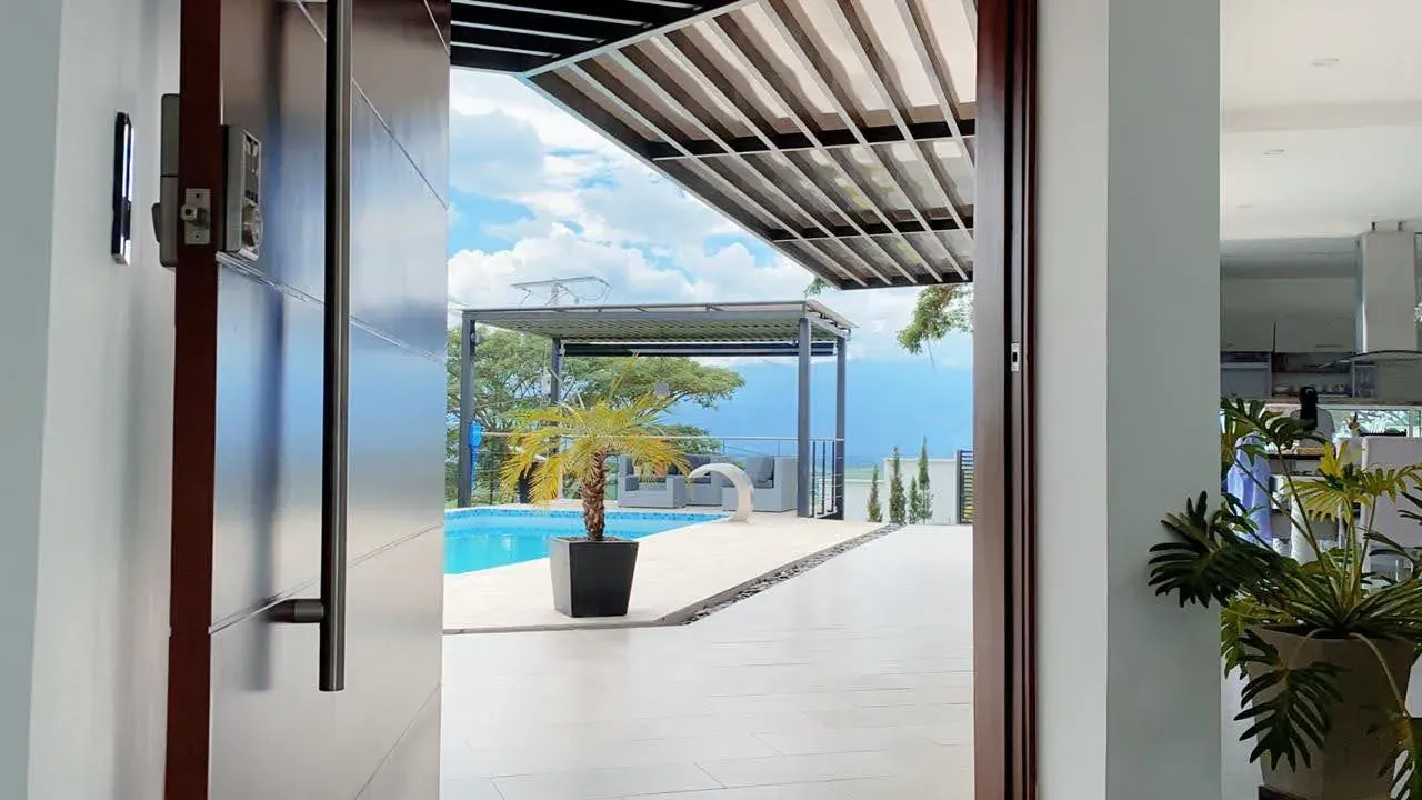 Entrance of a finished house opening onto a terrace with a pool and a pergola