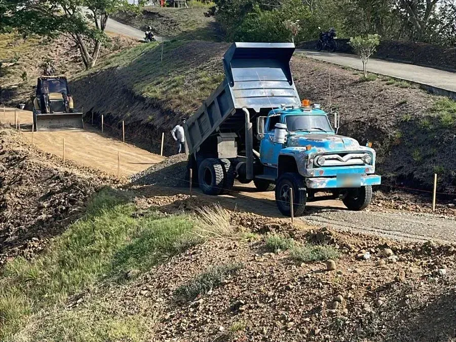 Dump truck unloading material on a hillside road under construction