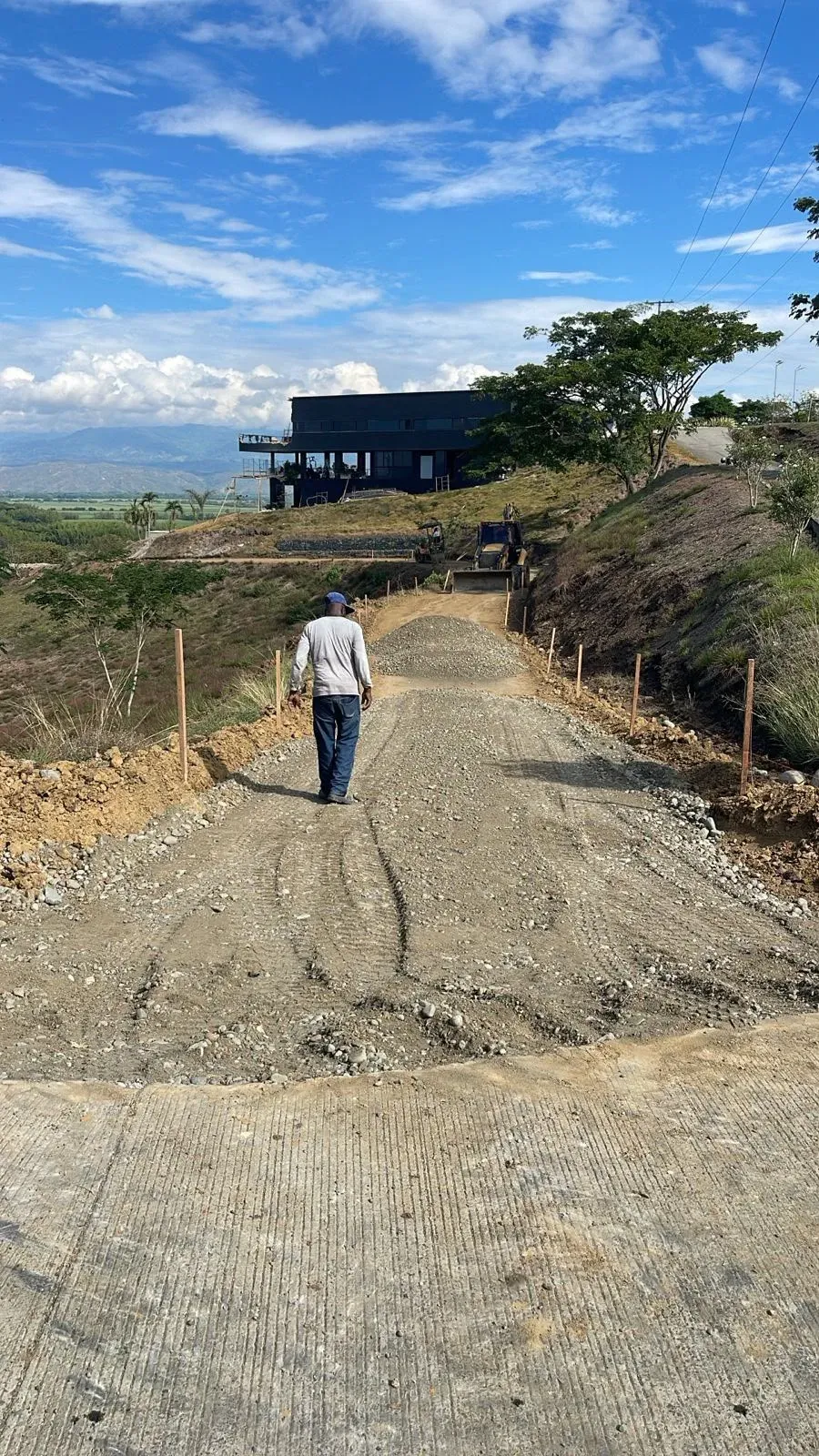 Internal road with a gravel base layer, climbing towards a house on the hill